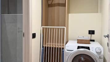 Un espace buanderie équipé d’un lave-linge et d’un étendoir.