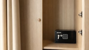 Une armoire en bois avec un coffre-fort noir, deux crochets et un petit bouton rond.