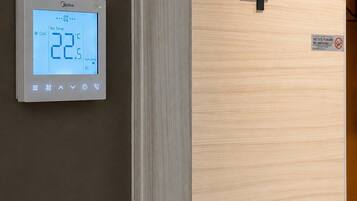 A digital thermostat displaying a temperature of 22.5°C, a wooden door with the number 4, and a no-smoking sign.