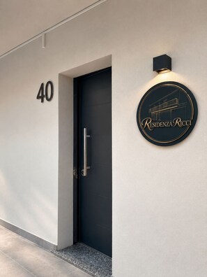 A modern building entrance with a dark door, a number '40' sign, and a circular sign with 'Residenza Ricci' text. - Residenza Ricci Airport BGY (Azzano San Paolo)