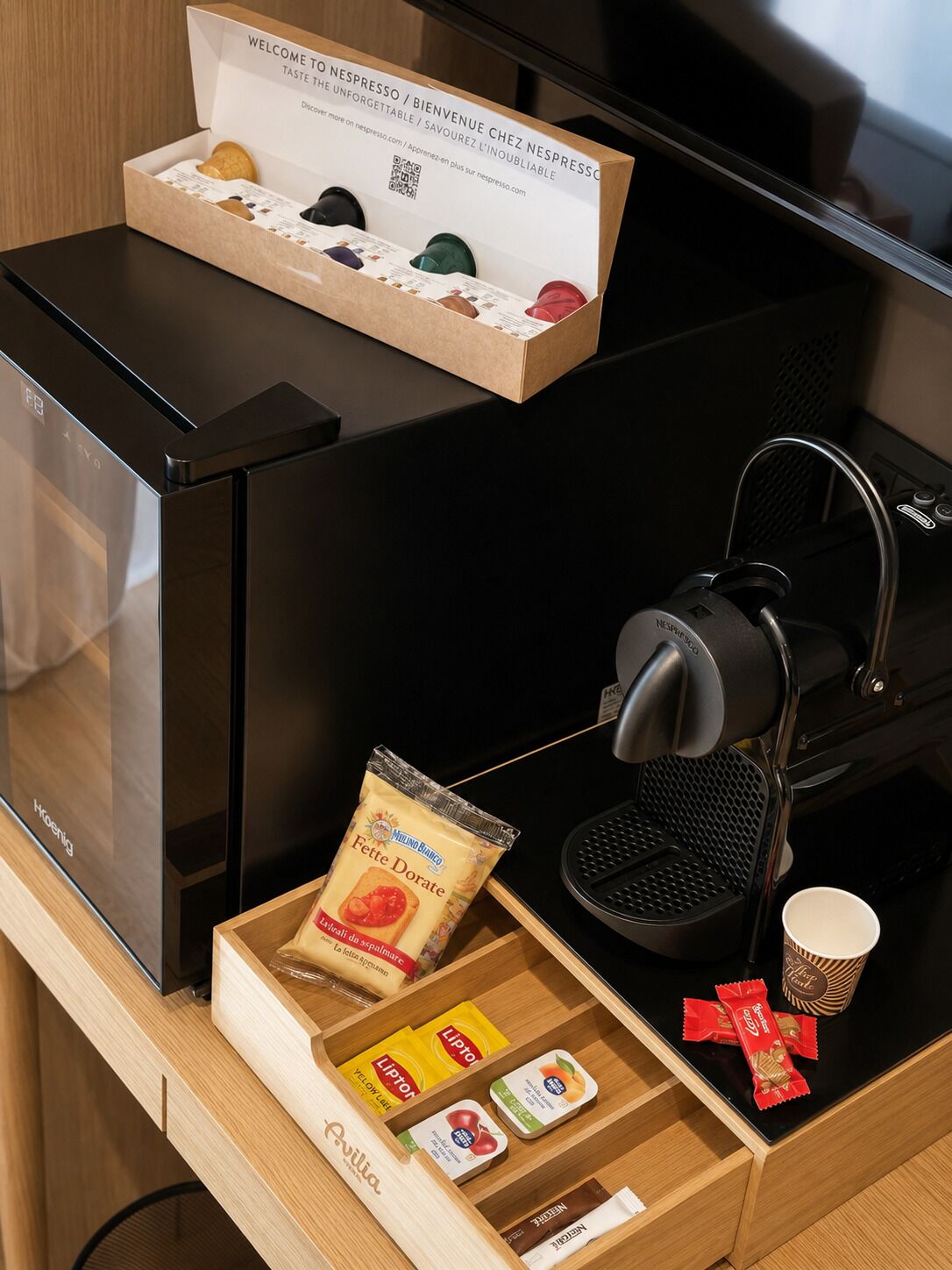 Une machine à café dotée d’un bac de récupération, d’une tasse à café et d’un tiroir contenant des en-cas et un paquet de Doritos.