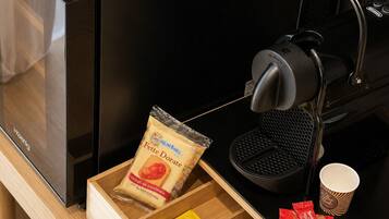 Une machine à café dotée d’un bac de récupération, d’une tasse à café et d’un tiroir contenant des en-cas et un paquet de Doritos.