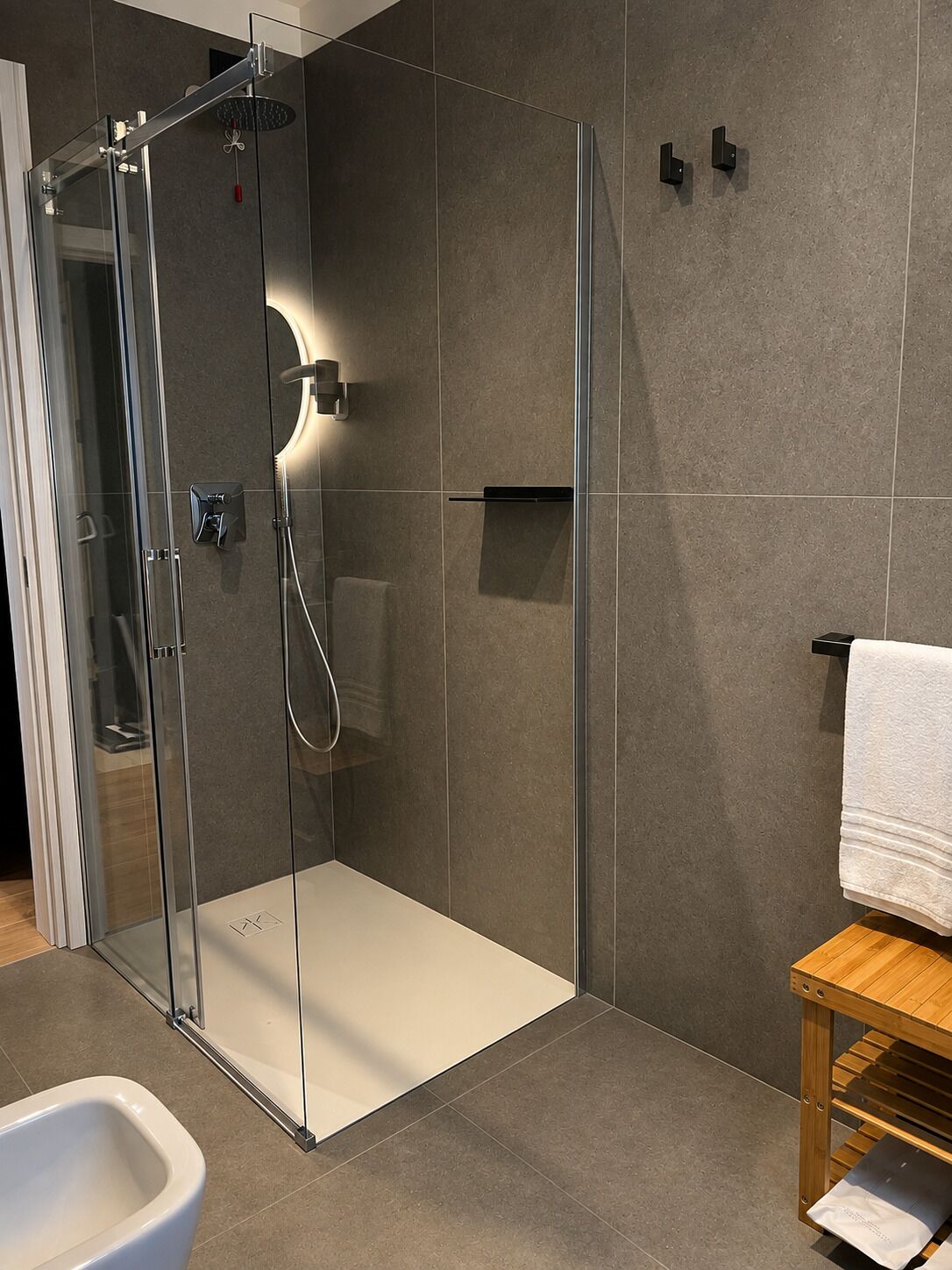 Une salle de bain moderne avec une douche à parois de verre, une baignoire blanche et un meuble-lavabo en bois.