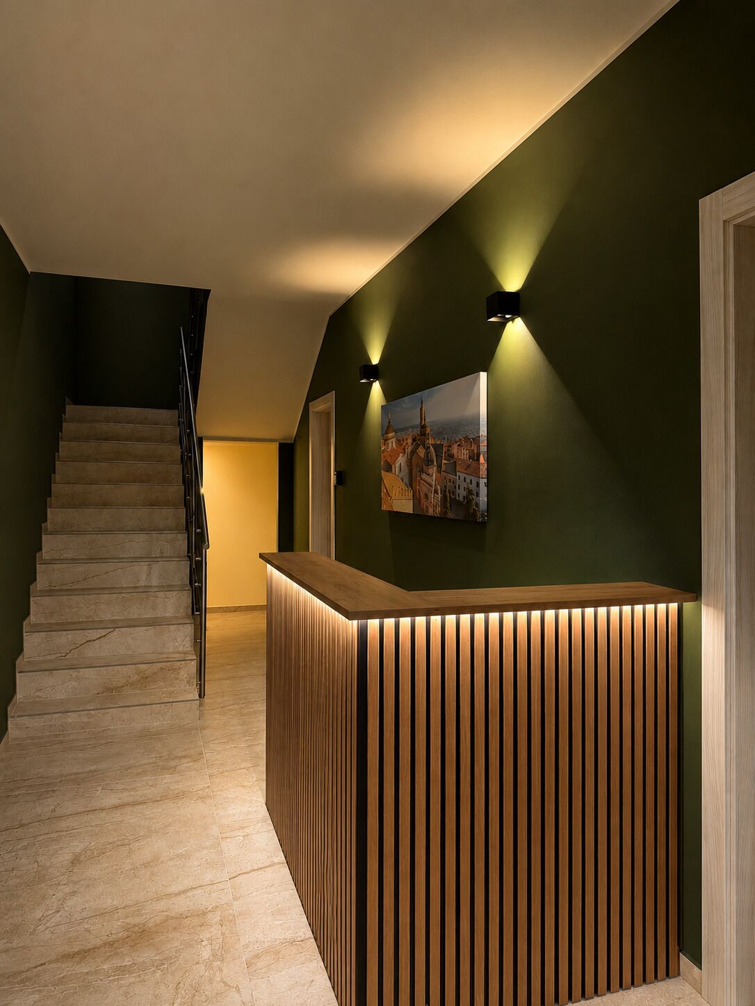 Un espace d’accueil avec un comptoir de réception en bois, un escalier et un tableau accroché au mur.