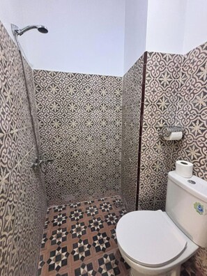 Een badkamer met betegelde vloer, een toilet en een douche.