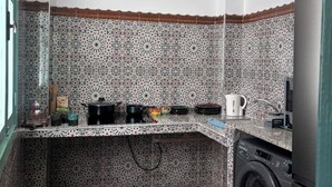 Una cocina compacta con baldosas estampadas, lavadora y lavamanos.
