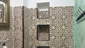 Un bany amb rajoles estampades, un lavabo, un vàter i una porta verda.