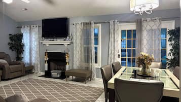 A living room with a fireplace, television, and dining area with chairs and a table.