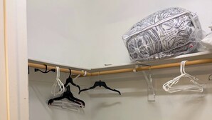 A closet with wooden flooring, white walls, and a wooden rod with hangers.