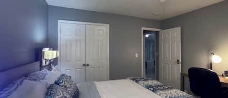 A bedroom with a bed, a desk, and a ceiling fan.