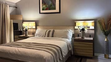 A hotel room with a large bed, bedside tables with lamps, a flat-screen TV, and a framed picture on the wall.