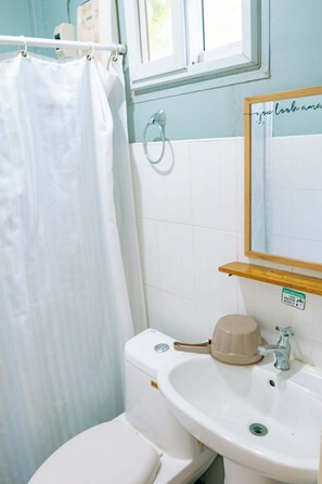 Ein Badezimmer mit Toilette, Waschbecken und einem Fenster über dem Spiegel.