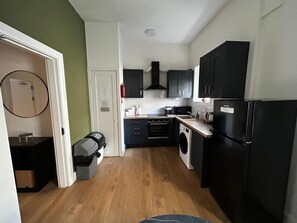 Eine kleine Küche mit Waschmaschine, Kühlschrank und Mikrowelle.