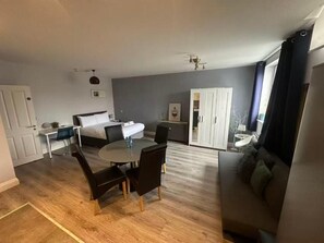 Ein Zimmer mit einem Bett, einem Esstisch mit Stühlen, einer Couch und einem Kleiderschrank.