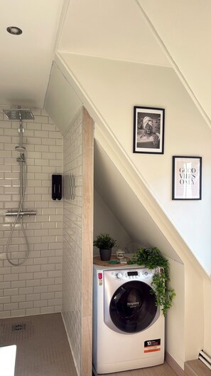 A laundry room with a washing machine, a shower, and a wall-mounted heater. - Le Cocon des Cordiers, Historic District (Mulhouse)
