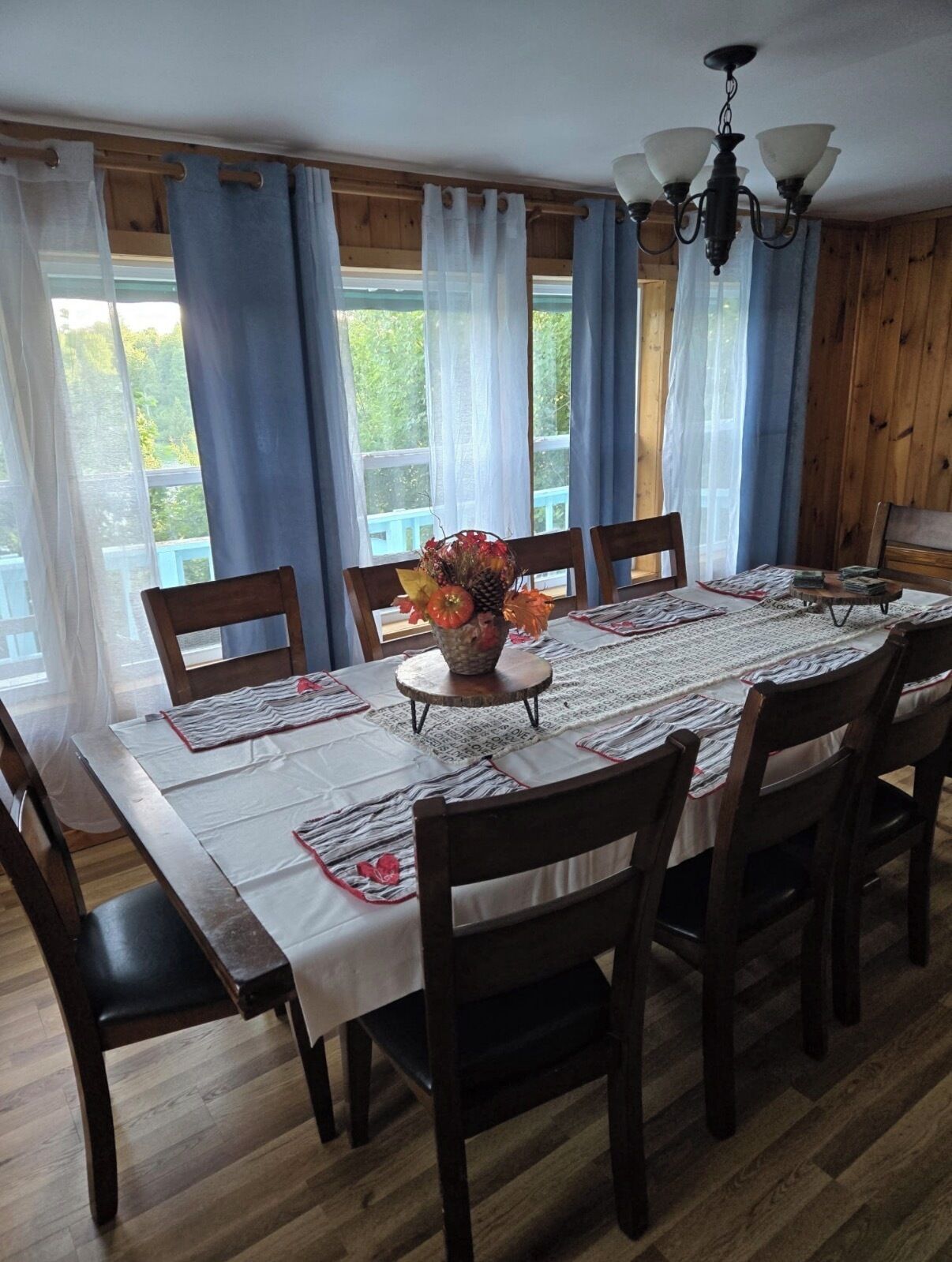 Un coin repas avec une table en bois, des chaises et un vase rempli de fleurs.