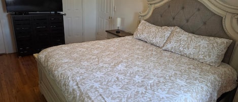 A bedroom with a bed, a television, a dresser, and a nightstand.