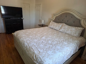 A bedroom with a bed, a television, a dresser, and a nightstand. - Serene Oasis - near JFK Airport, LIRR Train & USB (Queens)