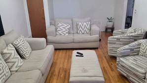 Uma sala de estar com sofá, pufe e poltronas listradas.