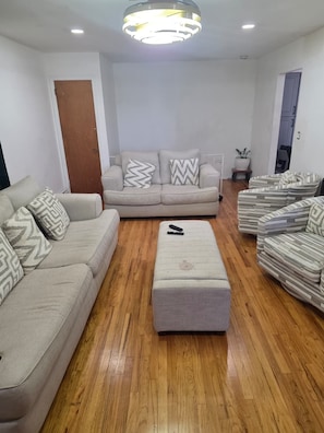 A living room with a sofa, ottoman, and striped armchairs. - Serene Oasis - near JFK Airport, LIRR Train & USB (Queens)