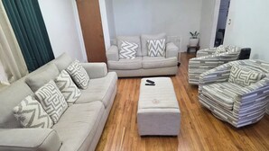 Uma sala de estar com um sofá bege, um banquinho combinando e uma poltrona listrada.