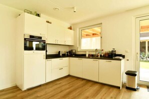 Una cucina moderna con mobili bianchi, un piano di lavoro nero e un forno in acciaio inossidabile.
