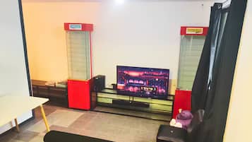A room with a flat-screen TV, speakers, a sofa, and a table.