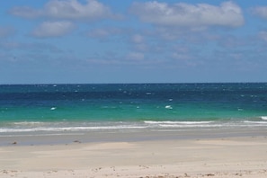 A beach with clear blue water and a sandy shore.