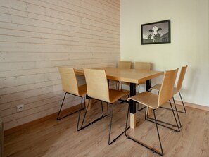 Ein Essbereich mit Holztisch, Stühlen, einem Wandbild und Holzboden.