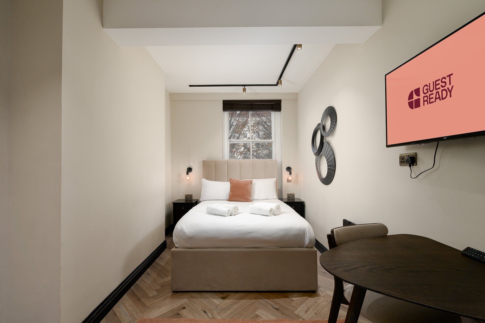 Une chambre d’hôtel moderne équipée d’un lit, de tables de chevet, d’un téléviseur et d’une table à manger.