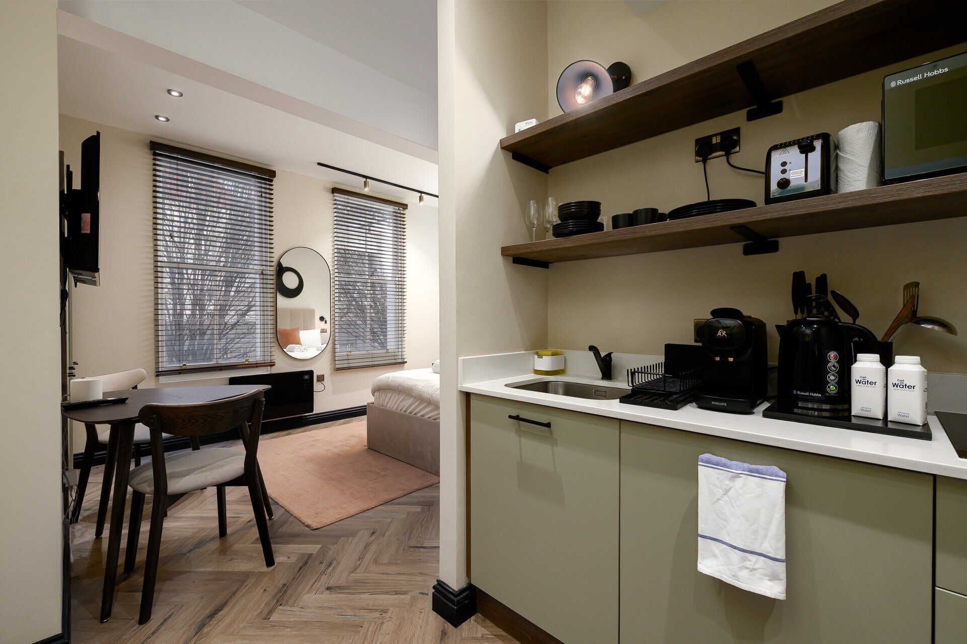 A compact kitchen with a coffee maker, kettle, and a water dispenser.