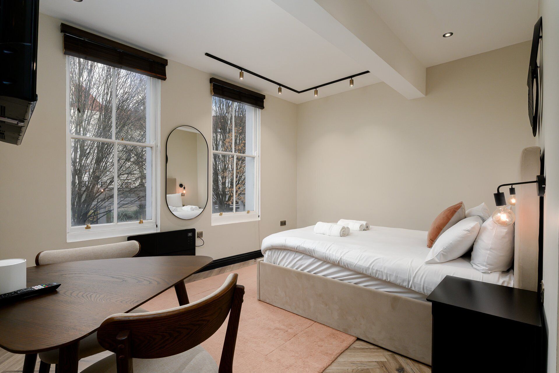 A bedroom with a bed, bedside table, chair, and a window with a view of trees.