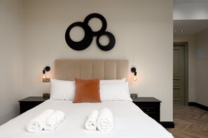 Ein Hotelzimmer mit einem Bett, zwei Nachttischen, einer Kopfteil und einer Wandleuchte.
