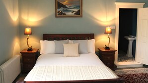 A bedroom with a large bed, two bedside lamps, a painting on the wall, and a door leading to a bathroom. - South Hill House, Historic Georgian manor with capacity for 52 guests (Delvin)