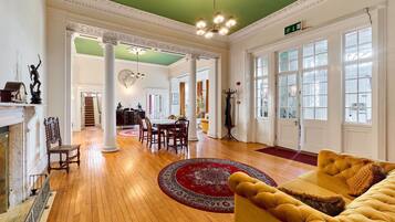 A spacious room with a wooden floor, a round red rug, a yellow sofa, and a fireplace.