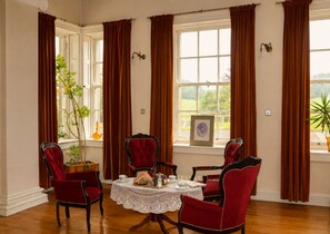 A dining room with a round table, four chairs, and a view of the outdoors through large windows.