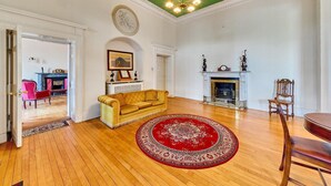 A spacious living room with a yellow sofa, a red patterned rug, a fireplace, and a green ceiling. - South Hill House, Historic Georgian manor with capacity for 52 guests (Delvin)