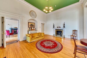 A spacious living room with a yellow sofa, a red patterned rug, a fireplace, and a green ceiling. - South Hill House, Historic Georgian manor with capacity for 52 guests (Delvin)