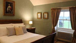 A hotel room with a bed, a nightstand, a lamp, a window with curtains, and two framed pictures on the wall. - South Hill House, Historic Georgian manor with capacity for 52 guests (Delvin)