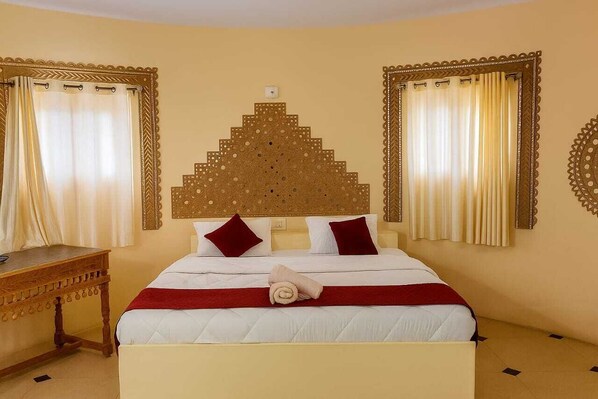 A hotel room with a bed, curtains, a wooden nightstand, and a wall decoration.