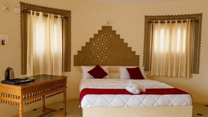 Una habitación de hotel con una cama, una mesita de noche de madera y un cabecero decorativo.
