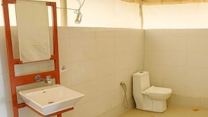Un baño con lavamanos blanco, inodoro y zona de ducha.