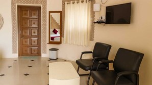 A room with a patterned door, a television mounted on the wall, and two black chairs.