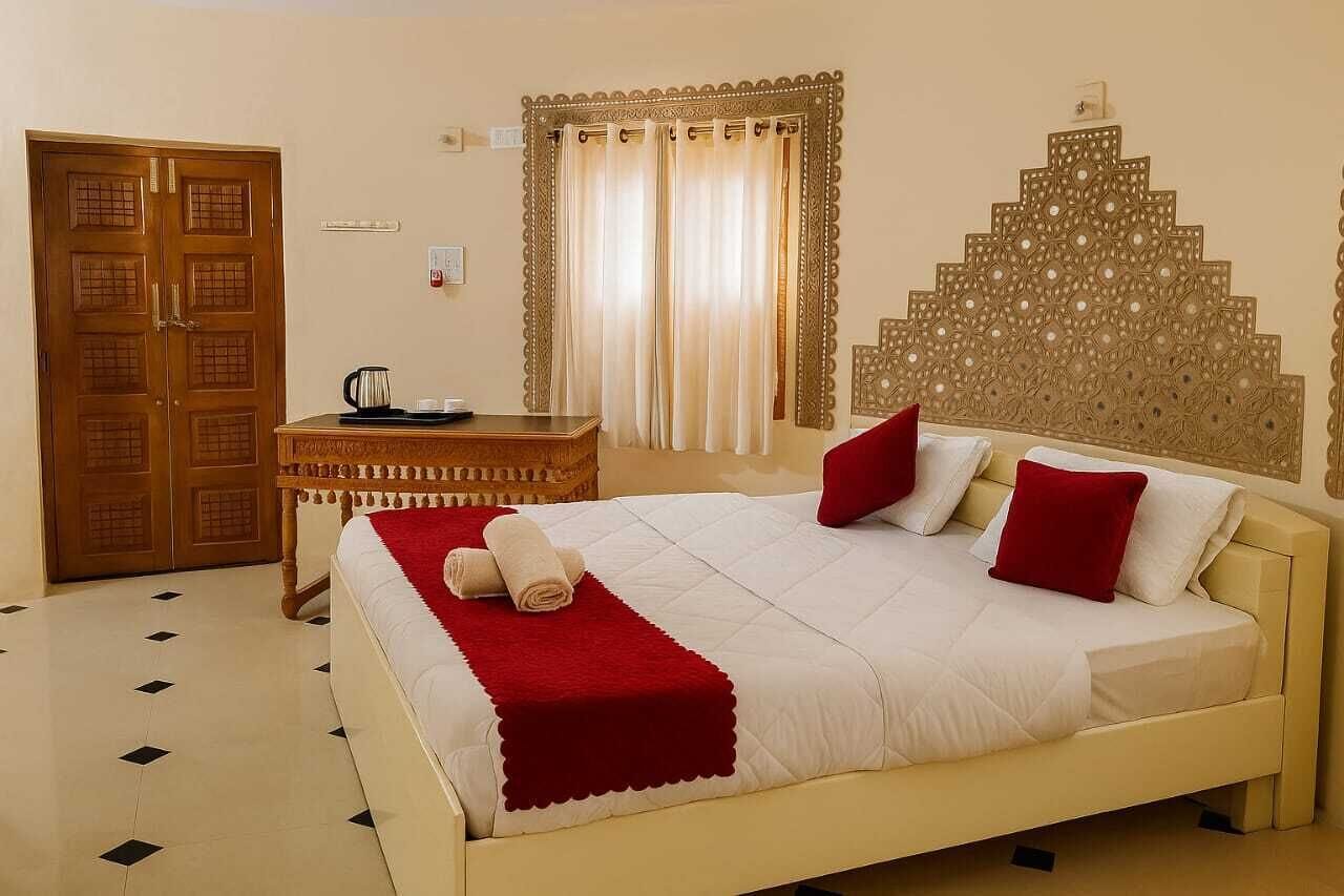 A hotel room with a bed, a desk, a coffee maker, and a decorative headboard.