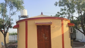 A small, single-story building with a central door and a small set of steps leading up to it.