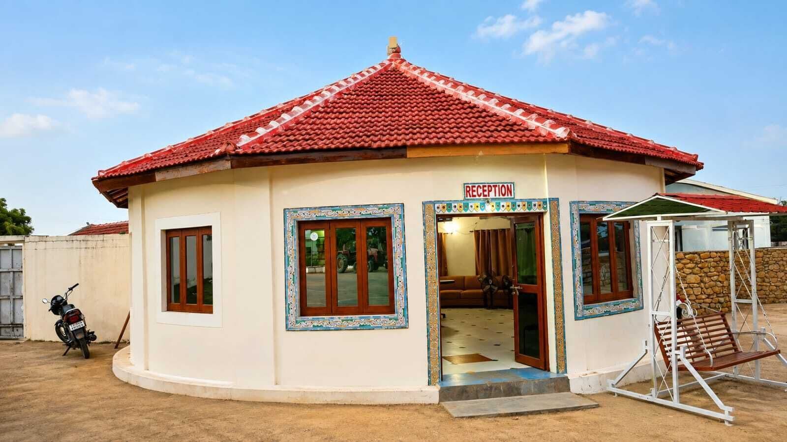A reception area with a red-tiled roof, a sign indicating 'RECEPTION', and a swing chair outside.