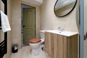 A bathroom with a toilet, sink, mirror, and a door. - GuestReady - Elegant living in Euston (London)