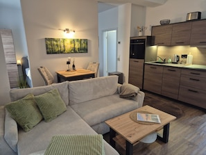A modern living room with a sofa, a coffee table, and a dining area with a table and chairs. - Cozy "Waldoase" vacation rental in the heart of the Vogtland region. Pet-friendly! (Auerbach/Vogtland)