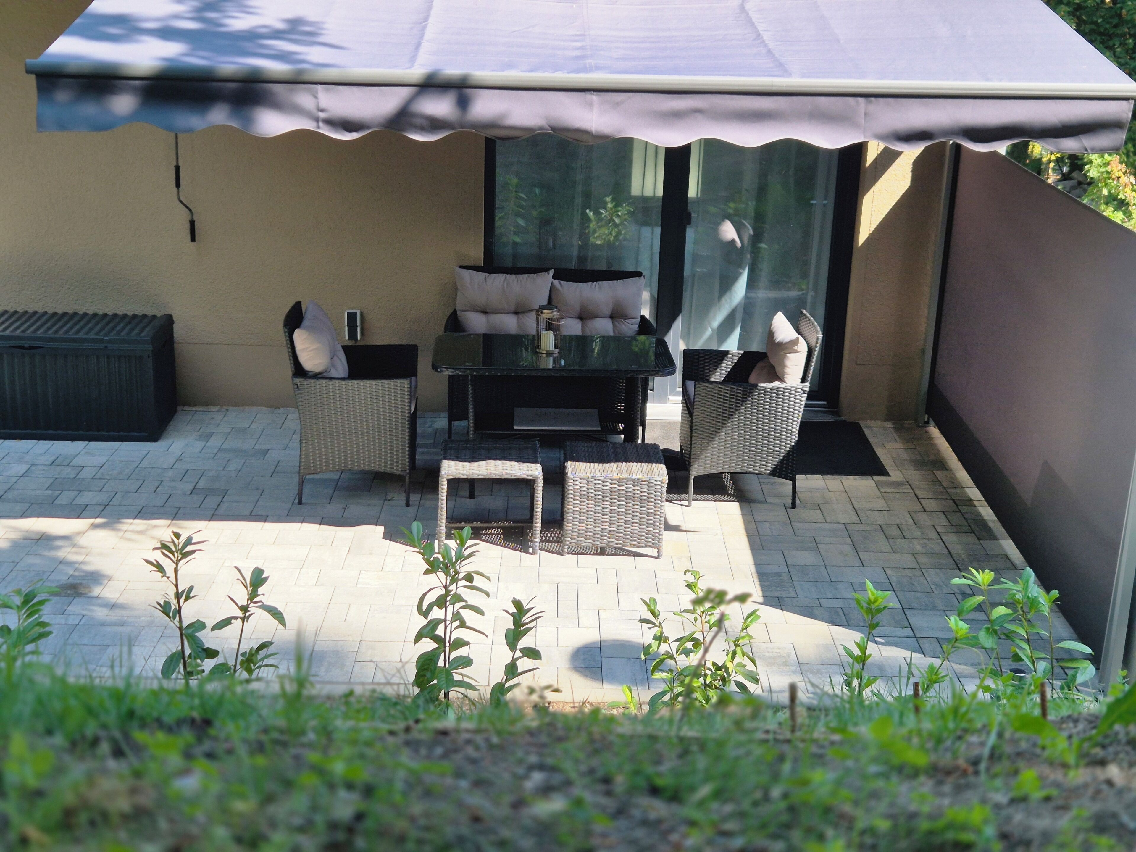 An outdoor patio with a table and chairs, a covered seating area, and a small garden.