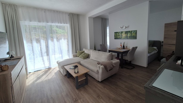 A modern living room with a sofa, coffee table, and a dining area with chairs.